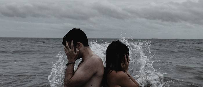 Detektive ermitteln beim Verdacht auf Ehebruch hier Symbolfoto von 2 Personen, die im Wasser Rücken an Rücken stehen