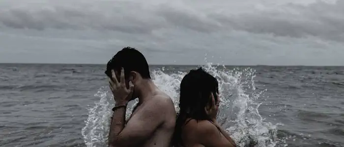 Detektive ermitteln beim Verdacht auf Ehebruch hier Symbolfoto von 2 Personen, die im Wasser Rücken an Rücken stehen