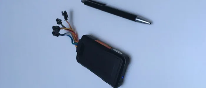 GPS Sender für PKWs und ein Kugelschreiber zum Größenvergleich.